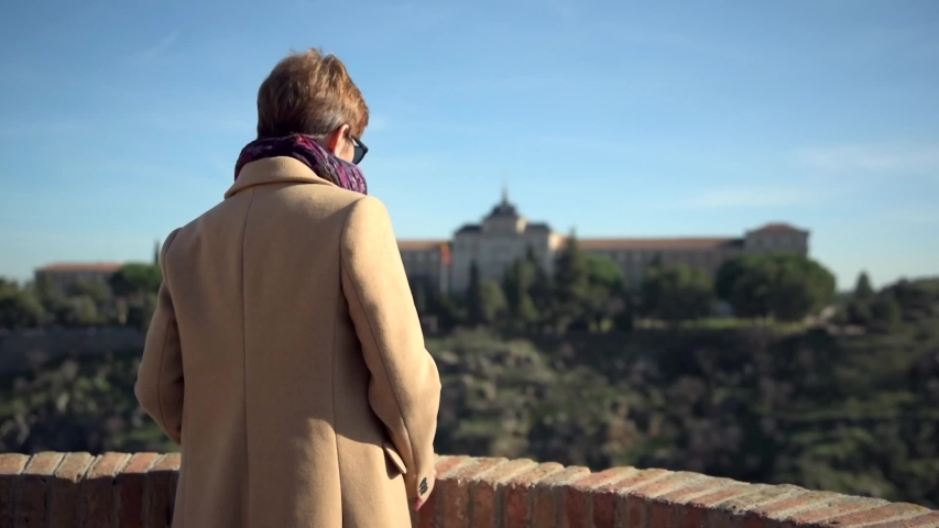 A tourist contemplates the landscape from a viewpoint in Toledo, Spain