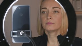 Female shoots video with a smartphone, illuminating the face of the led ring