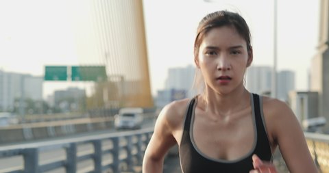 Portrait of fit and sporty young woman doing exercise in city. Woman running with concentrate at the city. Slow motion shot.
