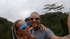 Couple travel selife video by Hawaii waterfall on Hawaii, Big Island, Akaka Falls. Happy cheerful young couple on travel having fun together