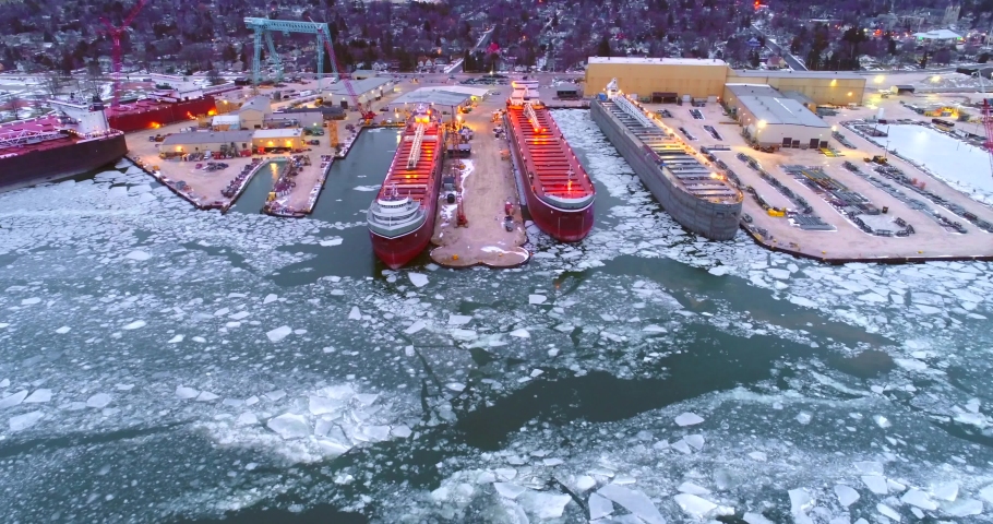 Giant Great Lakes freighter ships being built, refurbished, repaired, in icy cold waters, aerial view.