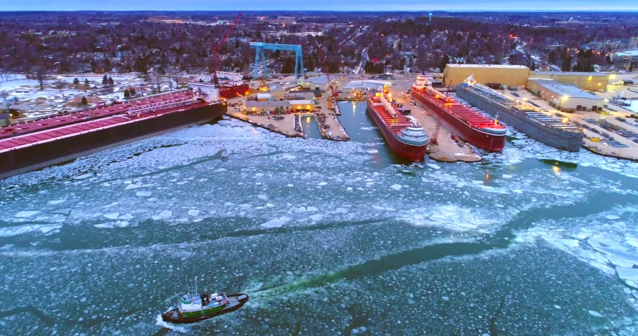 Giant Great Lakes freighter ships being built, refurbished, repaired, in icy cold waters, aerial view.