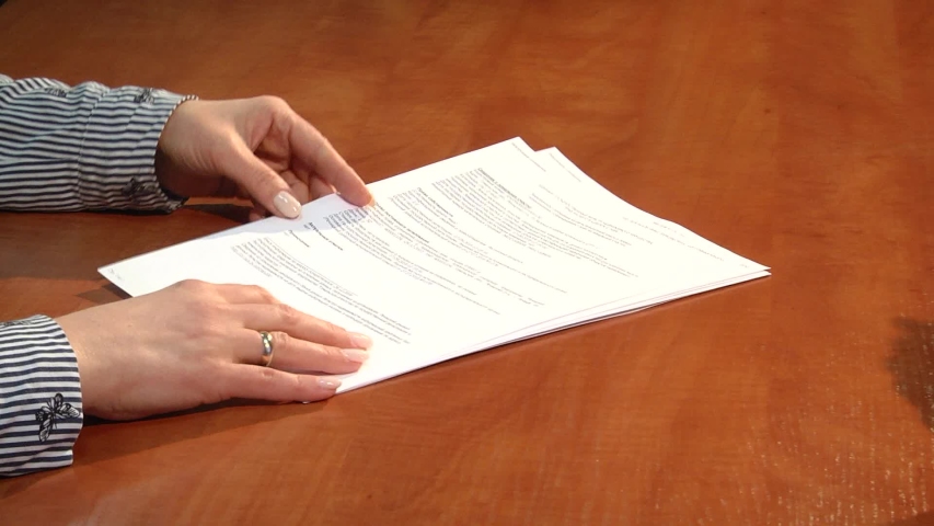 Employment interview with female applicant handing over a file containing her curriculum vitae to the businessman
