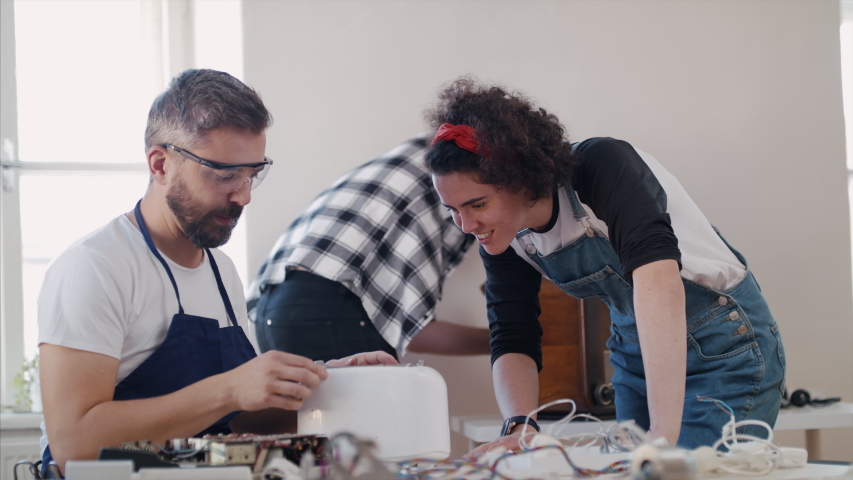 Group of people at repair cafe repairing household electrical devices. | Shutterstock HD Video #1044609688