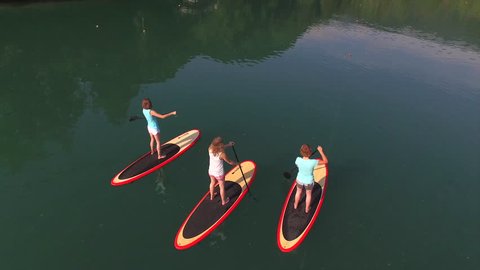 AERIAL: Flying above surfer girlfriends SUP boarding on Bled lake in beautiful morning
