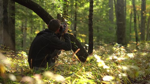 Young male photographer in the forest taking nature pictures with a dslr during early autumn or late summer