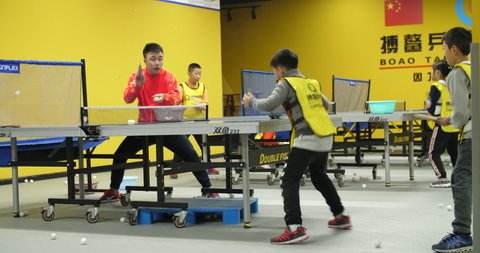 Chengdu,Sichuan/China-January 14th 2020: young man coach focus on training kid playing ping-pong Chinese Children  practice table tennis in the sports club during winter holiday