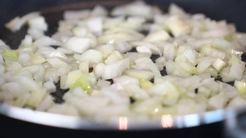 to cook woman fries onions in a pan in olive oil close-up. the olive oil is soon heated to fry the onions. natural and healthy dishes. vegan food. self-isolation cooking
