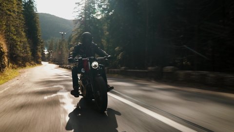 Bicaz Gorge, Romania - 11.07.2019: Crane rolling shot of a Harley Davidson motorcycle driving on a mountain road during fall