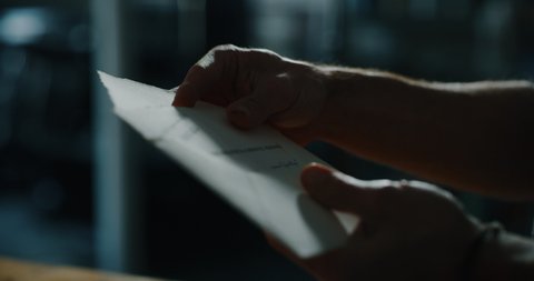 Cinematic close up shot of man is putting a letter in an envelope before sending it. Concept of correspondence, calligraphy, communication
