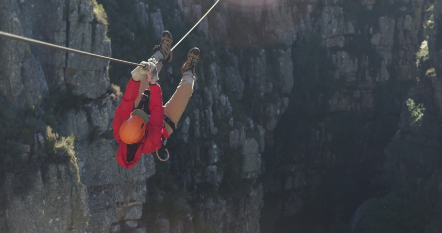 Rear view of a Caucasian man zip lining on a sunny day in mountains, climbing up the rope, slow motion. Adventure Vacation in South Africa