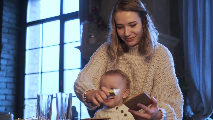 mom and son collect a gingerbread house in a dark blue kitchen