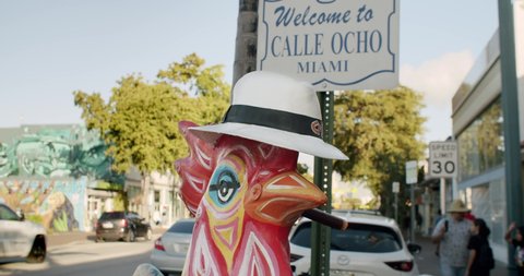 Little Havana, Miami, Florida/U.S.A. - January 08 2020: Welcome to Calle Ocho sign and colorful signature rooster chicken at the Little Havana entry in Miami, Florida in cinematic slow motion