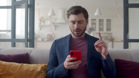 Closeup focused business man reading email on phone at home office. Portrait of male freelancer getting idea at remote workplace. Handsome guy texting on smartphone on couch in slow motion.