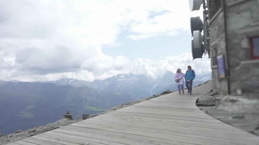 Elder couple walking on a wooden trail towards a lookout of the glacier in Switzerland