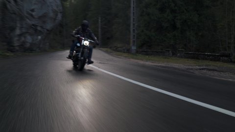 Bicaz Gorge, Romania - 11.07.2019: Crane rolling shot of a Harley Davidson motorcycle driving on a mountain road during autumn