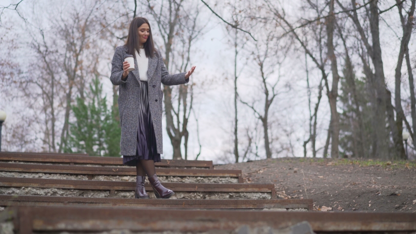 The girl is standing and nervous in the autumn park. Brunette in the park in the fall.