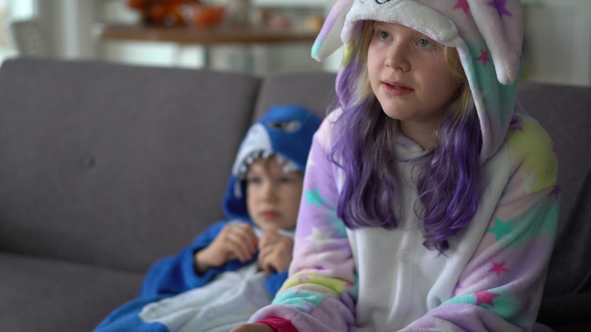 happy family in kigurumi playing a game console on the TV in the living room at home