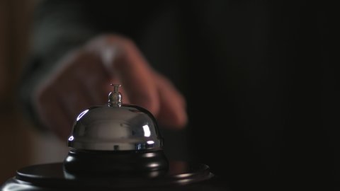 Close-up of a call to the front Desk of the hotel. Men finger presses the bell.