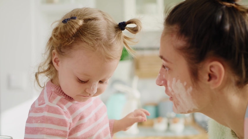 Handheld view of mum and little girl playing with flour. Shot with RED helium camera in 8K   Royalty-Free Stock Footage #1044714214