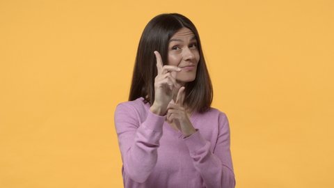 Slow-motion assertive cheeky middle-aged modern urban woman pointing finger pistol at camera, wink and nod, made choice, hinting at you, choosing person, found excellent candidate, yellow background
