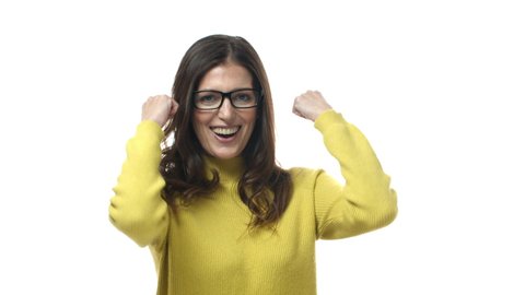 Win, excitement and success concept. Lucky brunette female in glasses celebrating victory, shaking hands in hooray gesture, say yes, fist pump and smiling upbeat, celebrate victory, white background
