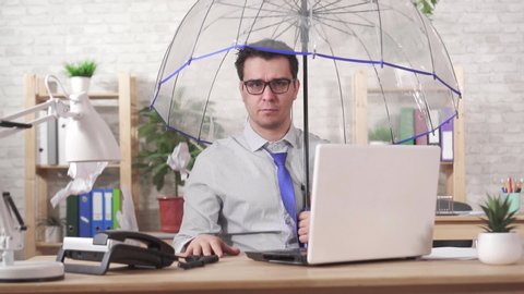 Concept excessive work,man office worker takes cover with an umbrella from a falling heaps of paper slow mo