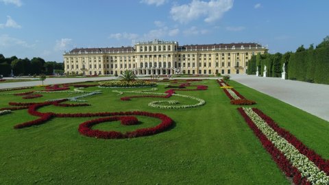 VIENNA AUSTRIA - JULY 10. 2019 aerial drone shot of Schönbrunn Palace / Schonbrunn Palace – camera flying over baroque gardens with palm approaching garden facade of the palace climbing higher