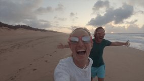 Couple running on the beach, woman holding camera selfie style. POV couple on vacation having fun on the beach  - Powered by Shutterstock - Get 15% off with code: PIKWIZARD15