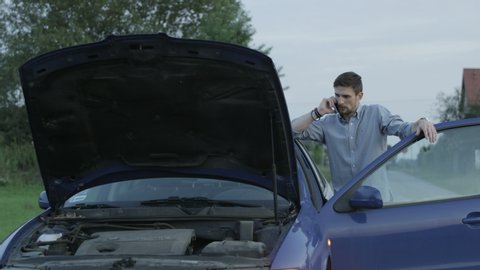 Opened Car Hood. Young Man Talking on the Phone