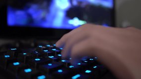 Closeup of male hand using illuminated PC gaming keyboard. Gamer is pausing game and leaving room for fresh air to keep in good mental health condition and prevent gaming addiction.