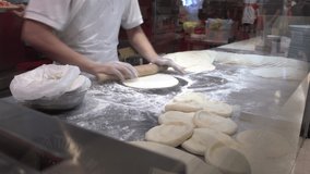 Baker kneading dough to make pizza base.