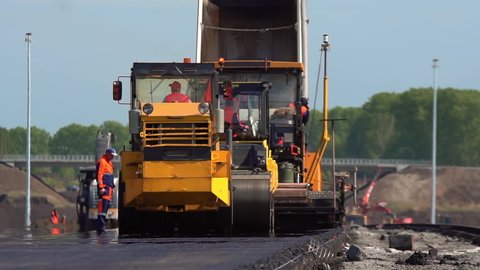 Construction of a new road. Machines lay fresh asphalt