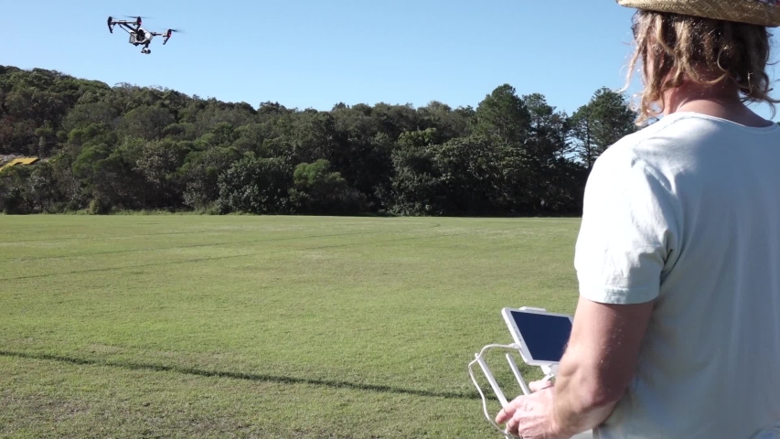 Male flying Drone in a sunny day in the park