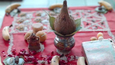 Embellished coconut beside figurine of the Deity, petals, laddu (Indian dessert) and dates, at a Hindu minority wedding 