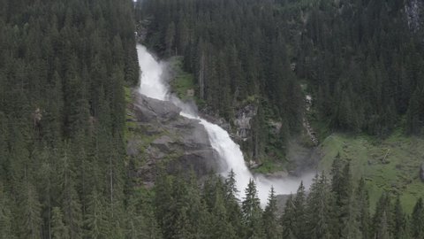 Aerial view of Krimml waterfall Cascades. Drone flight above strong water flow on rocks in spruce forest. Rainbow. Tirol, Salzburg land, Austria.