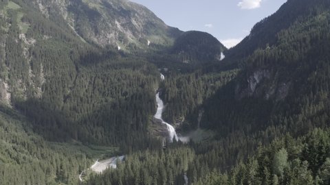 Aerial pan up view of Krimml waterfall in fir tree forest in Alpine mountains, Austria. Summer landscape. Sunny day.
