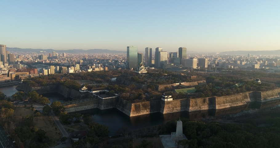 Water moat and stone walls of historic Osaka castle in the middle of modern city, Japan.
