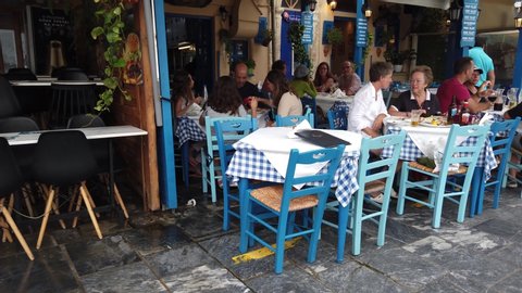 Crete Island, Greece - October 10, 2019: People are sitting in a street restaurant in a European city. Tourism and national cuisine concept.