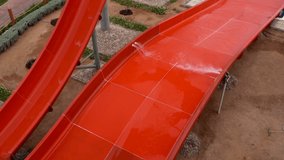 Top view of red plastic water slides at poolside. No people. Full hd top view video footage.