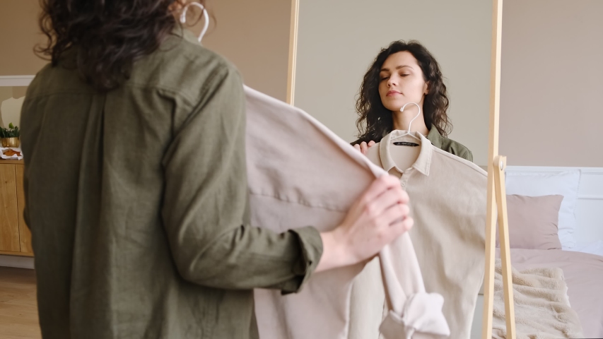 Young woman getting dressed looking in mirror. Trying on clothes enjoying herself.  Royalty-Free Stock Footage #1044776293