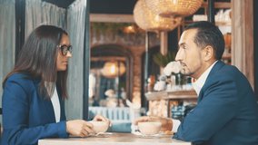 Two business people have business lunch. The woman and the man in a restaurant or a coffee shop are stirring and drinking coffee. Copy space.