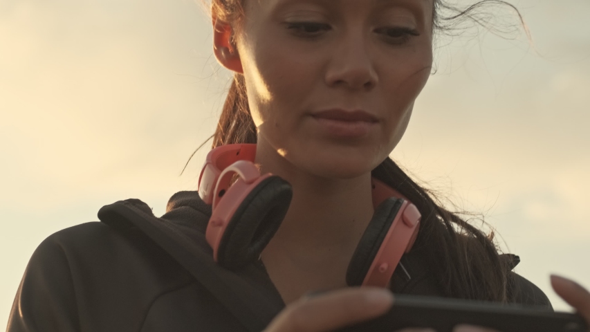 Close up view of Smiling pretty asian sports woman playing on smartphone outdoors