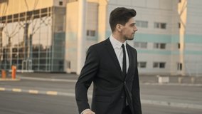 Close up view of Serious confident handsome businessman walking on parking near airport outdoors