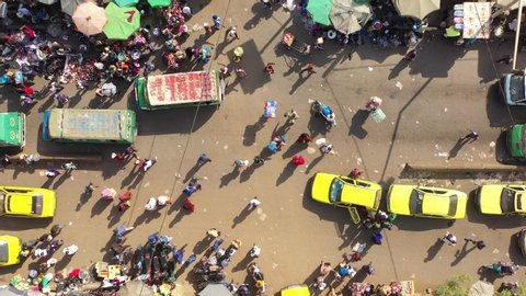 The drone rotates towards the right with a topdown view upon an intersection of a very busy and crowded but colourfull city street in Mali Aerial Drone Footage 4K