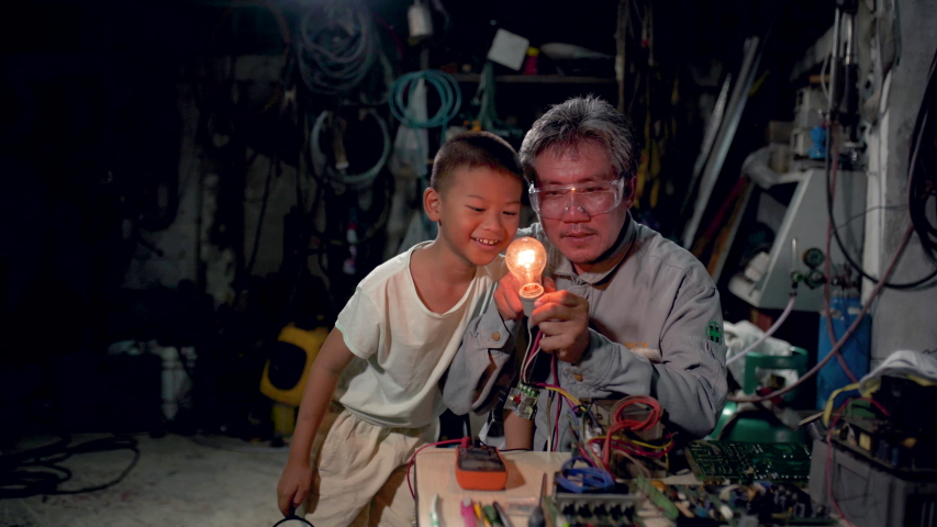 A child looking at the light bulb intently. Little boy with his uncle looking intently at the light bulb.