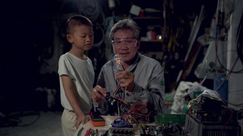 The little boy and the man looking the intently at the light bulb.