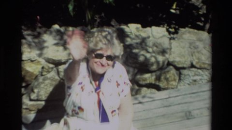 CARMEL CALIFORNIA USA-1982: People Looking Over Balcony And Woman In Sunglasses Waving From Bench