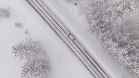DRONE, TOP DOWN: Car drives through a slippery snow covered intersection in Spokane, Washington. Flying above a car driving down icy road as blizzard covers the landscape with a deep blanket of snow. - Powered by Shutterstock - Get 15% off with code: PIKWIZARD15