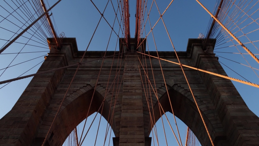 Moving glide shot under iconic Brooklyn Bridge tower over the Hudson River in New York City, USA. Concept of NYC as popular tourist travel destination, vacation in America.
 Royalty-Free Stock Footage #1044810544